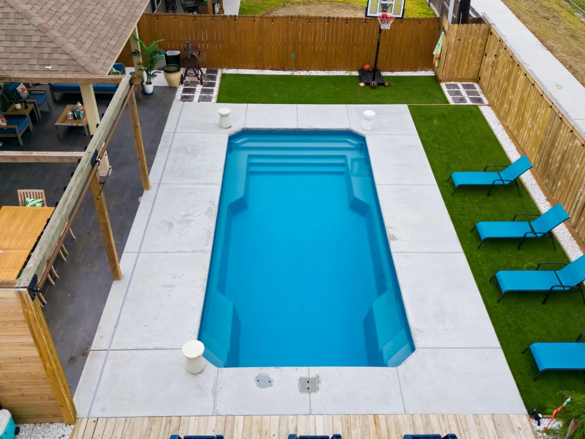 Barrier Reef Grande 29 fiberglass pool with entry steps and concrete decking installed by Copano Pools & Spas.