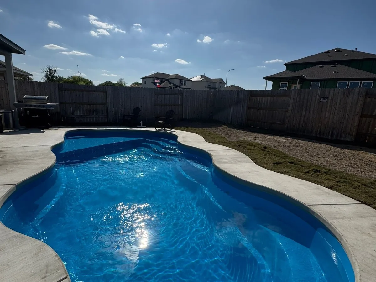 Barrier Reef Billabong Splash pool with a shallow ledge and curved concrete decking in Sunset Ridge, New Braunfels.