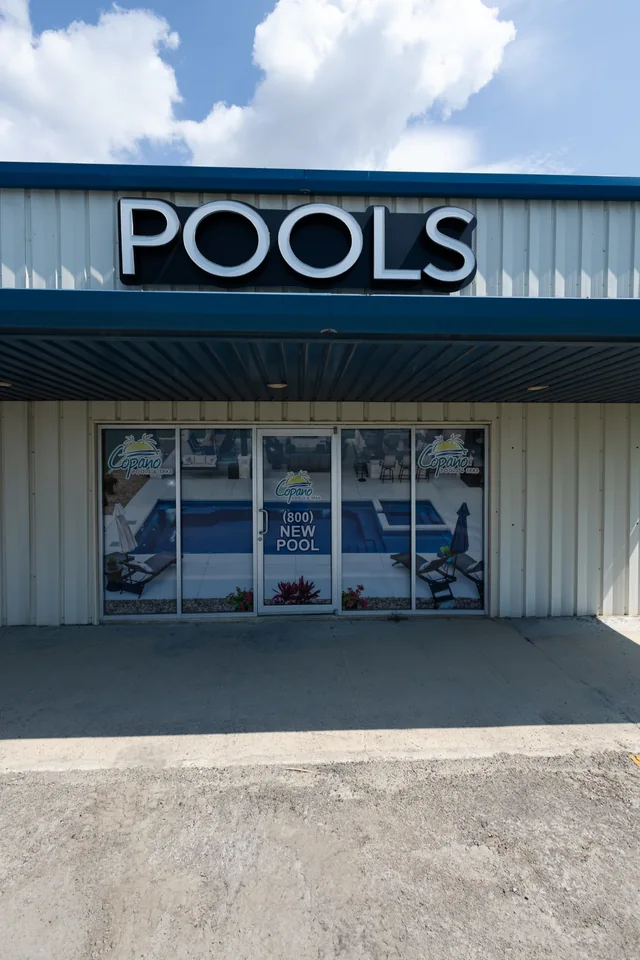 Copano Pools & Spas showroom entrance with blue trim and a large POOLS sign.